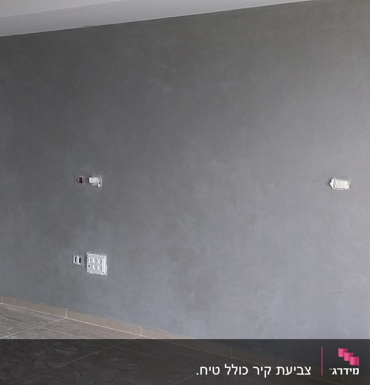 קיר צבוע באפור עם דלי צבע על הרצפה